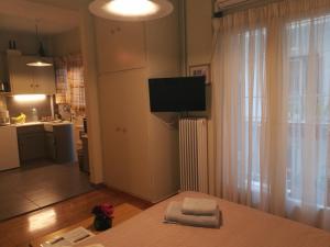 uma sala de estar com uma televisão na parede e uma cozinha em Koukaki ideal studio for 2 em Atenas