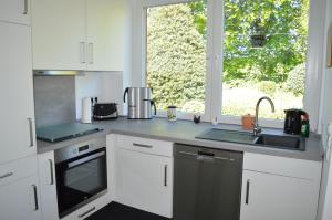 cocina con armarios blancos, fregadero y ventana en Ferienwohnung Gravemeier, en Ladbergen