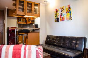 uma sala de estar com um sofá de couro e uma cozinha em Austral Rentahome Diego de Velazquez em Santiago