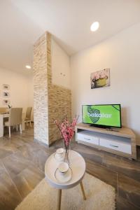 ein Wohnzimmer mit einem TV und einem Tisch mit Blumen in der Unterkunft Apartman Dendo in Zadar
