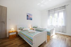 ein weißes Schlafzimmer mit einem Bett und einem Fenster in der Unterkunft Apartman Dendo in Zadar