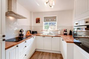 una cocina con armarios blancos y fregadero en Taylor Cottage en St Andrews
