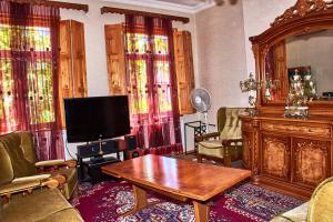 a living room with a tv and a wooden table at Guest House Svetlana in Gori