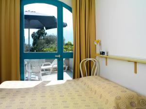a bedroom with a bed and a balcony with an umbrella at Casa Sandra Bertolini Alla Spiaggia in Nago-Torbole