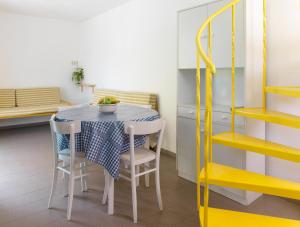 una mesa y sillas en una cocina con estanterías amarillas en Casa Sandra Bertolini Alla Spiaggia, en Nago-Torbole