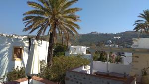 a palm tree and a white building with a umbrella at En Patmo Holiday Home in Patmos