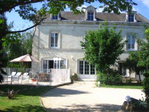 an old stone house with chairs and an umbrella at Maison d'hôtes Villa Richelieu in Châtellerault