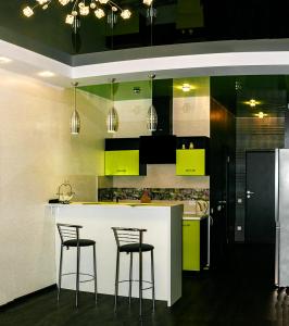 una cocina con armarios verdes y 2 taburetes en Апартаменты на 25 этаже., en Járkov