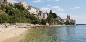 a beach with buildings on a hill next to the water at Villa Santino in Rab