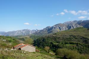 uma casa velha numa colina com montanhas ao fundo em La Terraza de Picos em Ortiguero