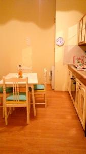 セゲドにあるAzúr Apartmanのテーブルと椅子付きのキッチン(壁掛け時計付)