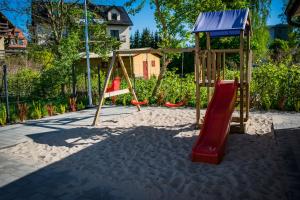 a playground with a slide and a swing set at Domki Aleja Róż in Międzyzdroje