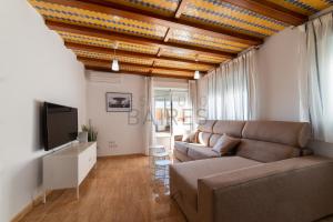 ein Wohnzimmer mit einem Sofa und einem TV in der Unterkunft Ático Plata in Cádiz