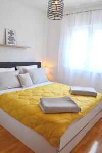 ein großes Bett mit gelber Bettwäsche und Kissen darauf in der Unterkunft Apartment Merak in Mostar