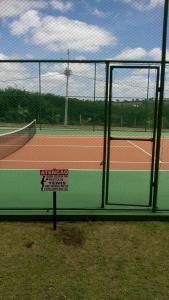 a tennis court with a fence with a sign on it at Gravatá winterville in Gravatá