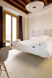 a bedroom with a large white bed and a table at Antidoto Rooms San Agustín - Recomendado para adultos in Toledo