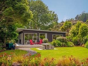 a small house in a garden with a patio at Flaxmill Accommodation in Whitianga