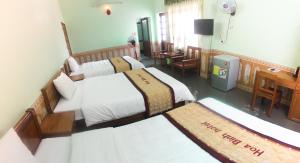 a hotel room with two beds and a desk at Hoa Binh Hotel in Dong Hoi