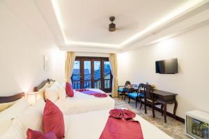 a hotel room with two beds and a desk at Hoian Central Hotel in Hoi An
