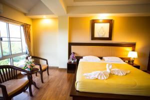 Madina Rayong Hotel في رايونغ: غرفة فندق عليها سرير وبجعة