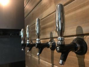 a row of chrome faucets on a wooden wall at Minato Hutte in Kobe