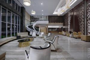 ASTON Banyuwangi Hotel and Conference Center في بانيووانجى: لوبي فيه مجموعة من الكراسي والطاولات