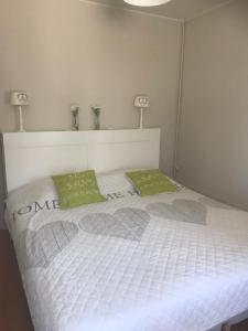 een wit bed met twee groene kussens erop bij Hotel Duinekeuntje in Oostende