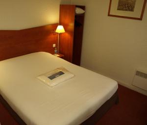 a bed in a hotel room with a book on it at Kyriad Chantilly in Chantilly