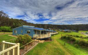 una casa azul en un campo junto a una valla en Beachcomber Holiday Park, en Potato Point
