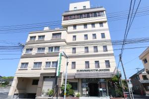 a tall white building on the corner of a street at Business Hotel Sansei in Saiki