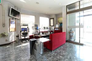 a living room with a red couch and a desk at Business Hotel Sansei in Saiki