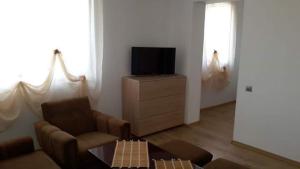 ein Wohnzimmer mit einem Sofa und einem TV auf einer Kommode in der Unterkunft Guesthouse Tatyana in Pŭrvenets