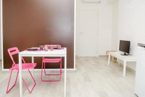 a white table with pink chairs in a room at La Casa del Riccio in Tindari