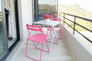 two pink chairs and a table on a balcony at La Casa del Riccio in Tindari