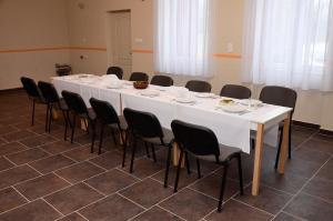 einen großen weißen Tisch mit schwarzen Stühlen in einem Zimmer in der Unterkunft Fatornyos Tanyasi Vendégház in Békéscsaba
