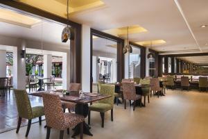 a dining room with tables and chairs and windows at Sukhothai Heritage Resort in Sawankhalok
