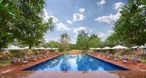 a swimming pool with lounge chairs and umbrellas at Sukhothai Heritage Resort in Sawankhalok