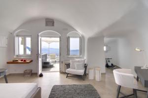 Sala de estar blanca con muebles blancos y mesa en Santorini Secret Suites & Spa, Small Luxury Hotels of the World, en Oia