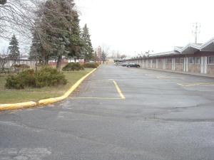 um parque de estacionamento vazio com carros estacionados ao lado de um edifício em Grand Motel Saint-Hubert em Longueuil