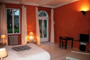 - une chambre avec des murs orange, un lit et une télévision dans l'établissement Le Couvent, à Apt