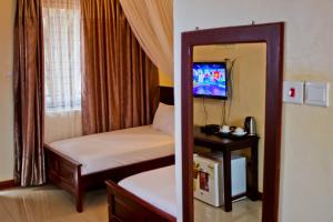 a small room with a bed and a mirror at Al-Nisaa Hotel and Spa in Jinja