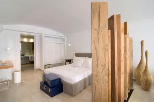 a bedroom with a bed and a room with a guitar at Santorini Secret Suites & Spa, Small Luxury Hotels of the World in Oia