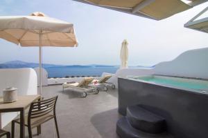 a room with a pool and a table and chairs at Santorini Secret Suites & Spa, Small Luxury Hotels of the World in Oia