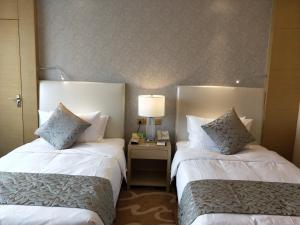 um quarto de hotel com duas camas e uma mesa com um candeeiro em Jinling Yujingwan Hotel Changyi em Changyi