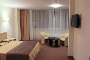 a hotel room with a bed and chairs and a television at Hotel Asteri in Kyiv