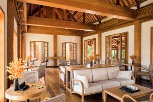 a living room with a couch and tables and chairs at Avani+ Luang Prabang Hotel in Luang Prabang