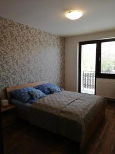 a bedroom with a bed with blue pillows and a window at Apartmán Skalnička - Tatranská Lomnica in Tatranská Lomnica +29 photos