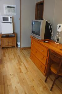 a television sitting on top of a wooden dresser at Motel Clair Mont in Sainte-Agathe-des-Monts