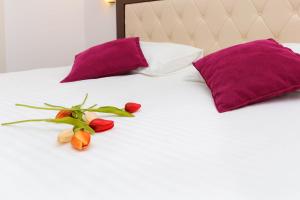 uma cama com almofadas roxas e flores em Aqua Breeze Apartments em Budva