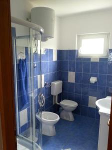 a blue tiled bathroom with a toilet and a shower at Apartments Lukacic in Tkon +49 photos